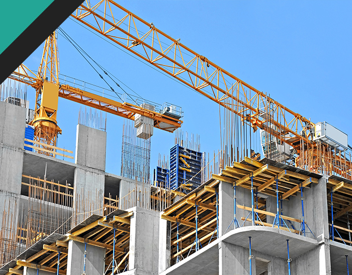 Construction site featuring a yellow crane lifting materials over a concrete structure under blue sky, showcasing building progress and engineering.