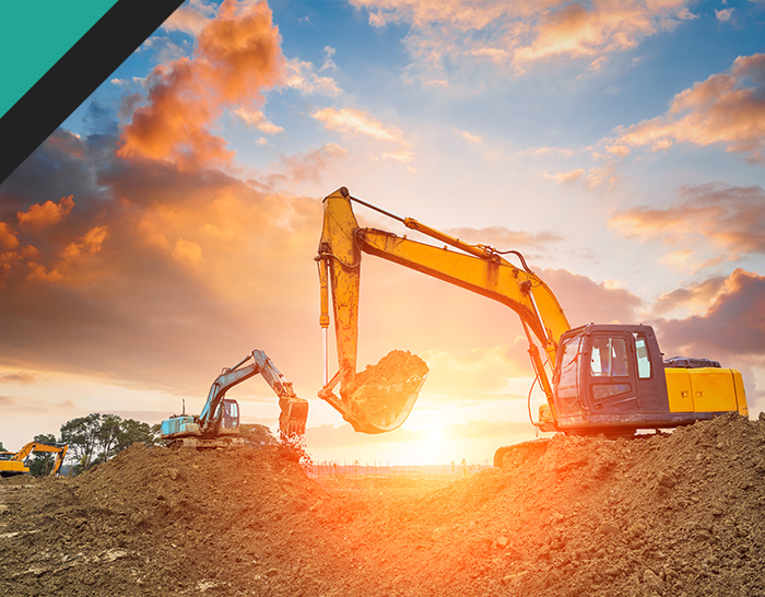 Excavators working on a construction site at sunrise, with dramatic clouds in the background. Heavy machinery digging earth and shaping the land.