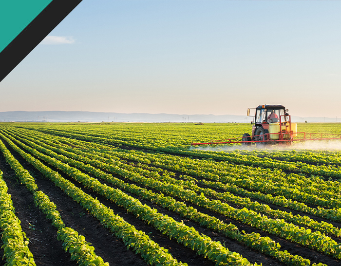 A tractor spraying crops in a green field under a clear sky, showcasing modern agricultural practices.